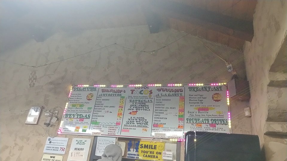 Outdoor seating beside a taco restaurant entrance.
